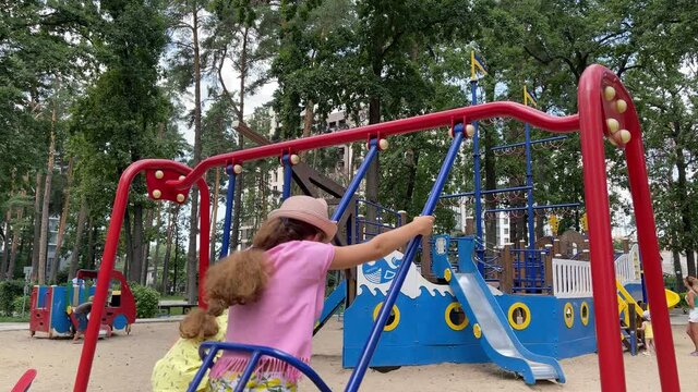 4k 2 girls swinging on a swing on a playground.