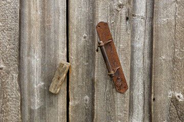 Iron handle on a wooden wall. The door is closed with a wooden catch.