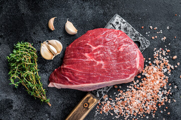 Fresh Raw rump beef cut or top sirloin cap steak on butcher cleaver. Black background. Top view