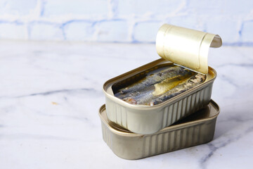 open tin of sardines on white tiles background.