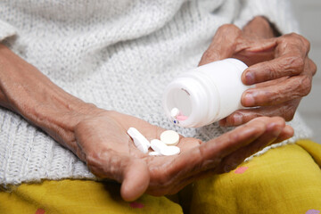 close up of pills and capsule on senior women's hand 