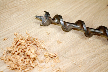 old drill bit with wood shavings on wooden background
