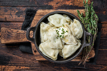 Homemade dumplings, vareniki, pierogi stuffed with potato in a pan. Dark wooden background. Top View