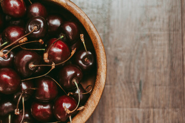 a cup of ripe red cherries on a wooden background