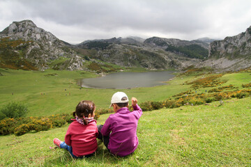 Fototapeta na wymiar Niños sentados en la montaña con lago al fondo