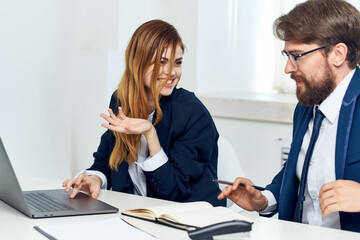 colleagues chatting in the office in front of a laptop professionals