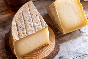 Close-up of a cured cheese cut into quarters, on a rustic wooden background.