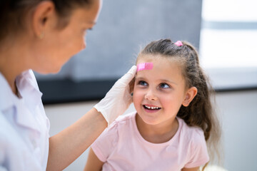 Applying Band Aid To Children Wound