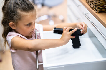 Kid With Gun. Girl Reaching For Pistol In Drawer