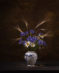Bouquet of wild flowers in a porcelain vase on a dark background