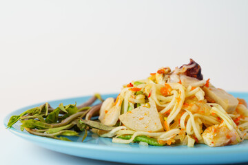 Green papaya salad with morning glory in ceramic blue plate isolated on white background.