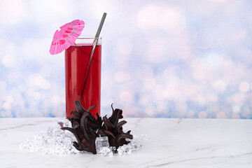 A glass of Roselle drinks with metal straw and whole Roselle fruits