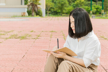 Obraz premium a woman sitting and writing a notebook in the park