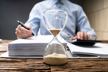 Hourglass At Desk. Legal Deadline