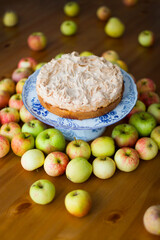 Apple pie with meringue on the top surrounded with green and red autumn apples
