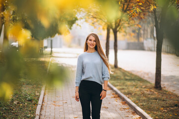 Young woman in blue sweater in autumn park