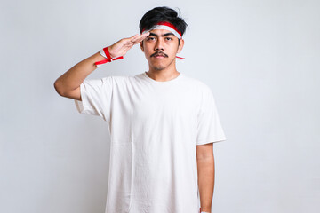 young indonesian man wearing a headband posing to salute the flag