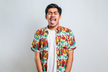 Young handsome asian boy wearing casual shirt sticking tongue out happy with funny expression.