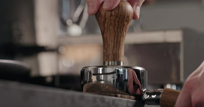 Slow motion tamping fresh ground coffee in basket of bottomless portafilter