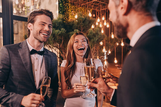 Group of people in formalwear communicating and smiling while spending time on luxury party