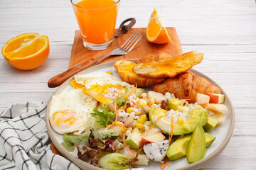 Croissant, fried egg, fresh green salad with fresh orange juice, breakfast