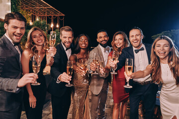 Group of people in formalwear toasting with champagne and smiling while spending time on luxury...