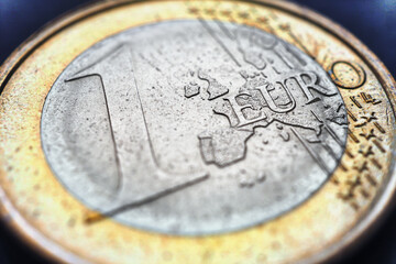 The 1 euro coin is lying on a dark surface. Focus on the name of the Eurozone currency. Close-up. Illustration about the economy, money and finance of the European Union. Macro