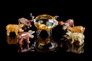 Pig figurines made of onyx, jasper, glass, gold on a black background