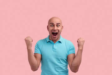 Happy surprised bald homosexual man with bristle won a prize, screams in excitement, has mouth wide...