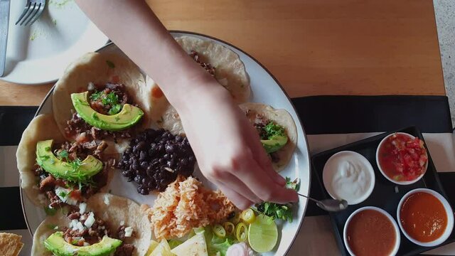Adding salsa on soft shell sirloin beef steak taco with avocado delicious mexican food