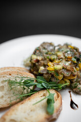 vegetable caviar or stew with eggplant, zucchini and bell pepper on white plate