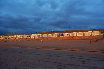 Golden beach cabins at Zandvoort in the Netherlands illuminated by the sunset - obrazy, fototapety, plakaty