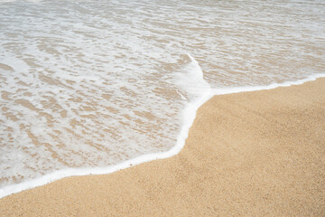 Wave with white foamy coastline beach.Soft waves of blue sea and sand on summer.
