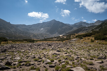 Foreground barren rocks, mountain hut and impressive distant rocky peaks on the hike track to...