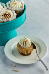 Mini pumpkin cheesecake on white plate with spoon, teal tray with more in background.