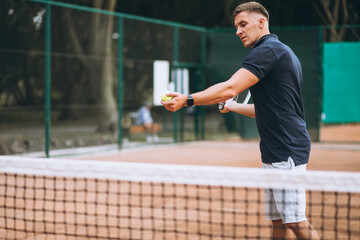 Young man playing tennis at the court