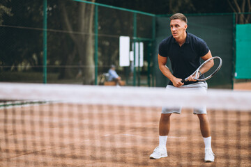 Young man playing tennis at the court