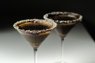 Alcoholic drink based on vodka and coffee liqueur served in a cocktail glass, decorated with chocolate, desiccated coconut and Halloween decoration in the shape of a spider