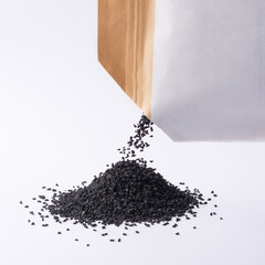 heap of black seeds, also known as black cumin or caraway or kalonji, poured out from a packet,...
