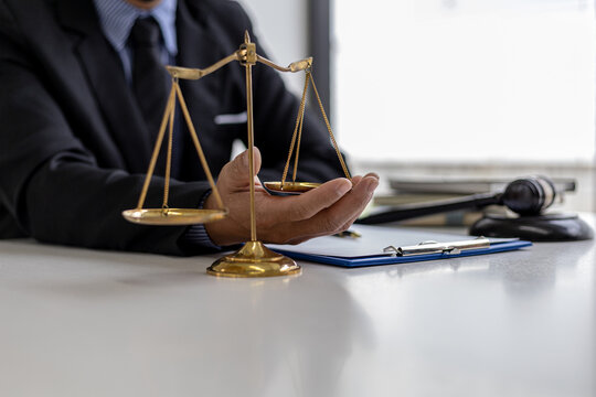 The male lawyer puts a second hand on the scales of justice on his desk, stating that the matter must be justified and not contrary to law and humanity. The concept of legal jurisprudence.