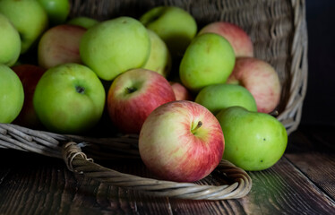 Red and green apples in the wicker basket. Autumn vibes. 