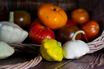Pattypan squashes and ripe tomatoes in the wicker basket. Autumnal composition with vegetables. Homegrown  healthy food. 