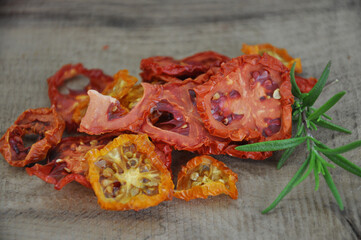 Dried tomato. A slide of sun-dried tomatoes which lie on a wooden background. flat top view. Freeze-dried vegetables. Dried spices healthy food. Spices. Sun-dried Italian tomato. Rosemary.