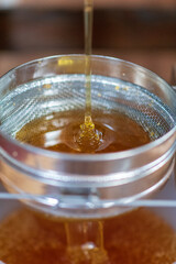 Drop of bee honey drip from hexagonal honeycombs