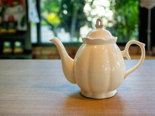 White teapot on a wooden table in a coffee shop