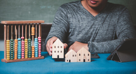 Businessman choosing mini wood house model from model on wood table, Planning to buy property. concept of Choose the best.