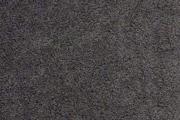 The mottled surface of the granite slab is finely speckled. Uniform texture of natural stone.