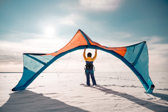 Sporty girl stands and hold snowkite in hands. Winter kitesurfing concept