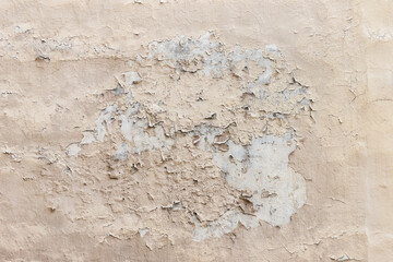 Shabby wall of an old house with uneven crumbling plaster. Yellow-gray abstract texture.