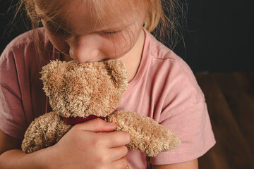 a lonely girl hugs a teddy bear. quarrels in the family. the child is scared. parents ' divorce